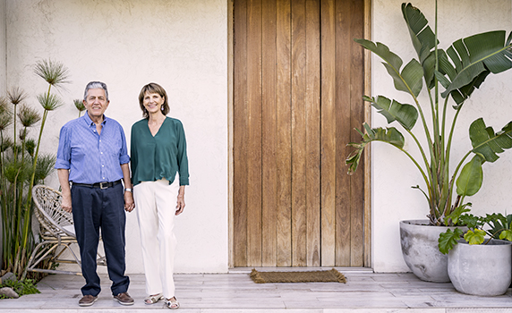 Photo of a couple standing in front of a villa in Florida with a large wooden door and tropical plants