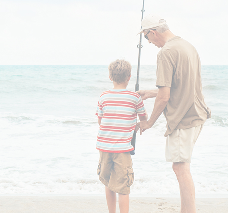 Photo of an adult teaching a child how to fish on the coast of the ocean