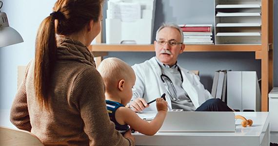 Photo of a doctor talking to their patient holding a baby 